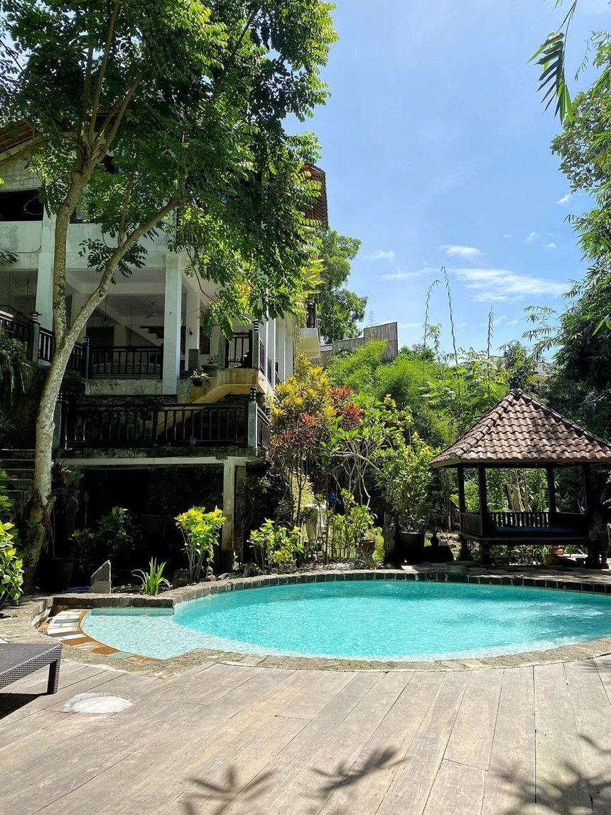Piscina rodeada de jardines tropicales con gazebo balinés